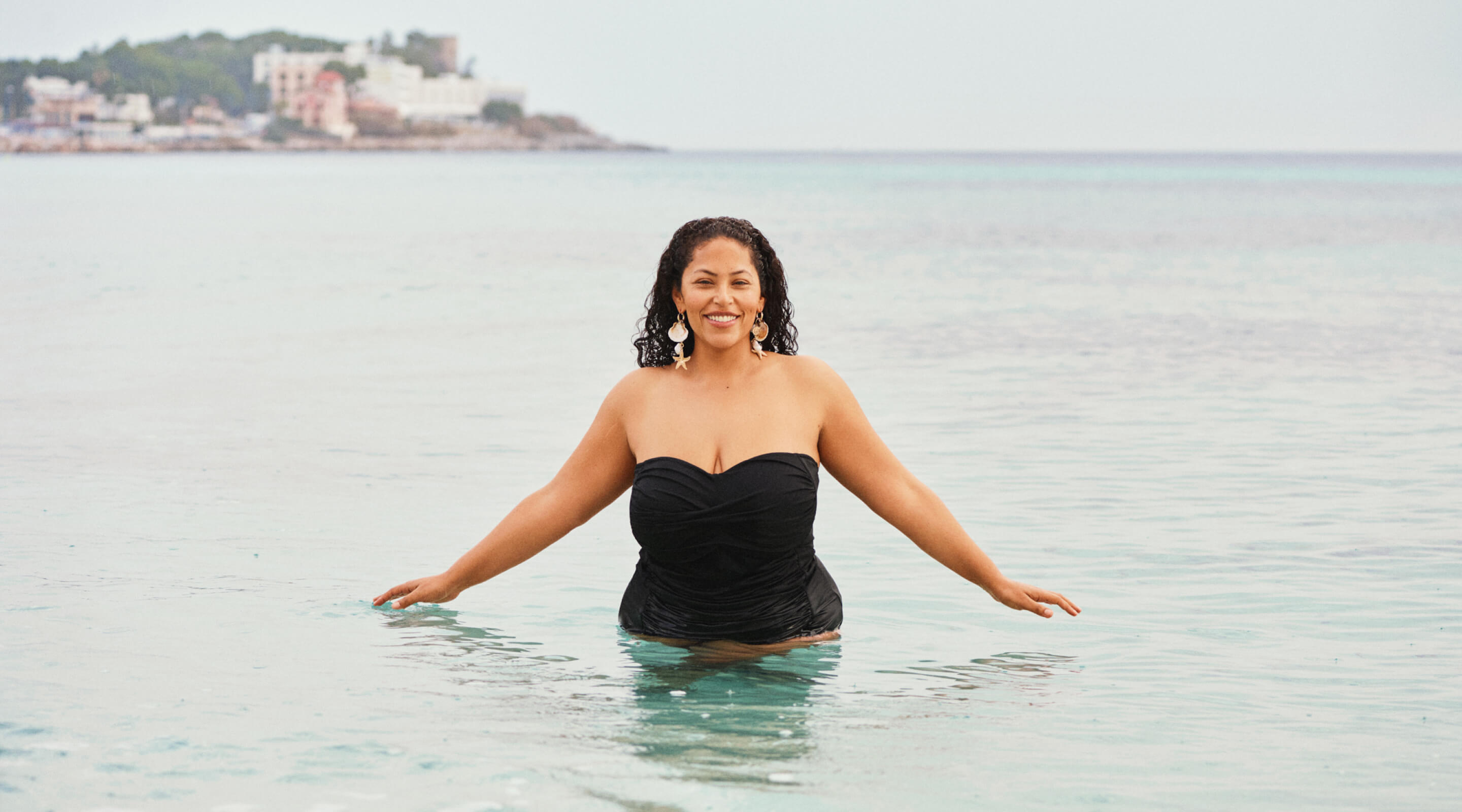 Model in a white bikini top by the harbour with swimmers